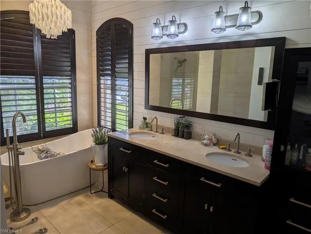 Bathroom with a bathtub, tile  flooring, and dual vanities
