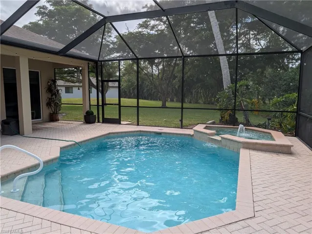 View of pool with an in ground hot tub, pool water feature, a patio, and a screened lanai