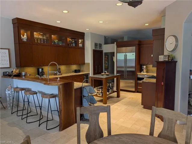 Kitchen with sink, backsplash, kitchen peninsula, Sub-Zero refrigerator, natural gas range and light stone counters