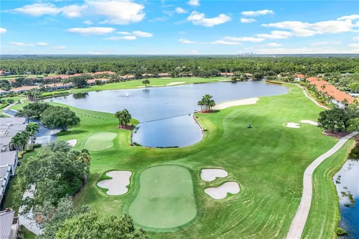 Aerial view of property's location featuring a golf course and nearby suburban area
