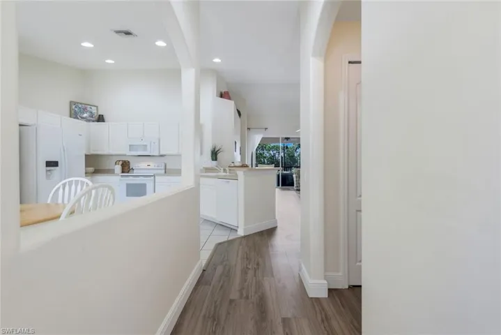 Hallway featuring arched walkways, light wood-style flooring, and recessed lighting