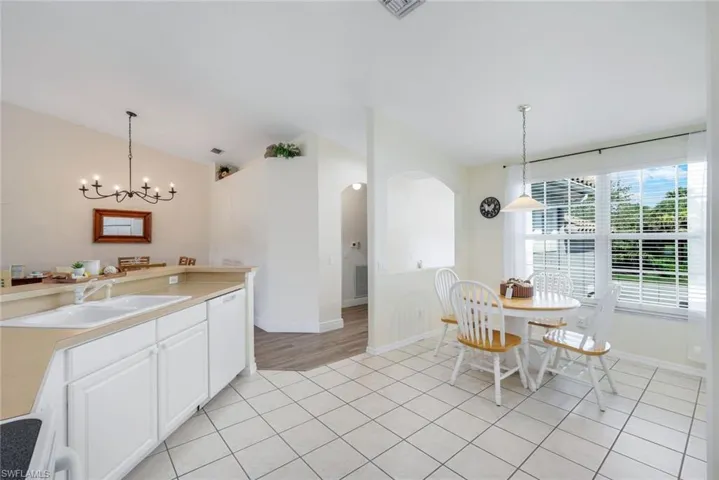 Kitchen with lofted ceiling, light countertops, arched walkways, light tile patterned flooring, and stove