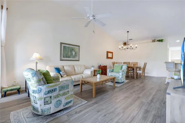 Living room featuring a chandelier, ceiling fan, wood finished floors, and high vaulted ceiling