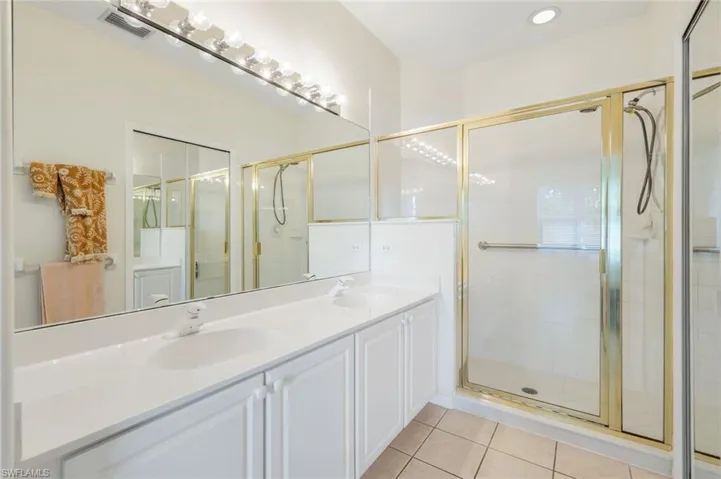 Bathroom with a stall shower, double vanity, and tile patterned flooring
