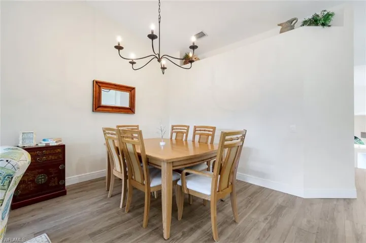 Dining space featuring a chandelier, light wood-style floors, and vaulted ceiling