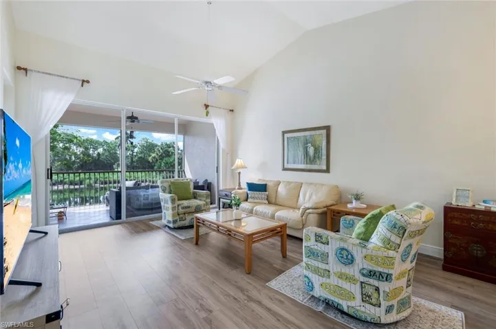 Living area with ceiling fan, wood finished floors, and high vaulted ceiling