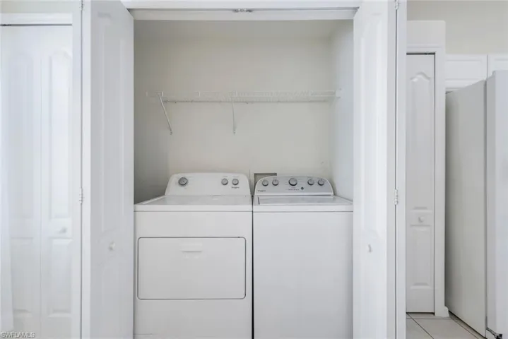 Laundry area with washing machine and dryer and light tile patterned floors