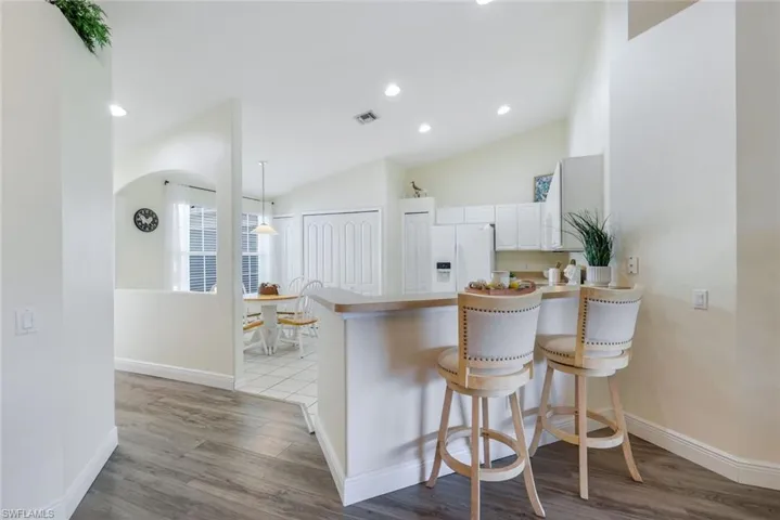 Kitchen with a peninsula, wood finished floors, lofted ceiling, arched walkways, and a kitchen bar