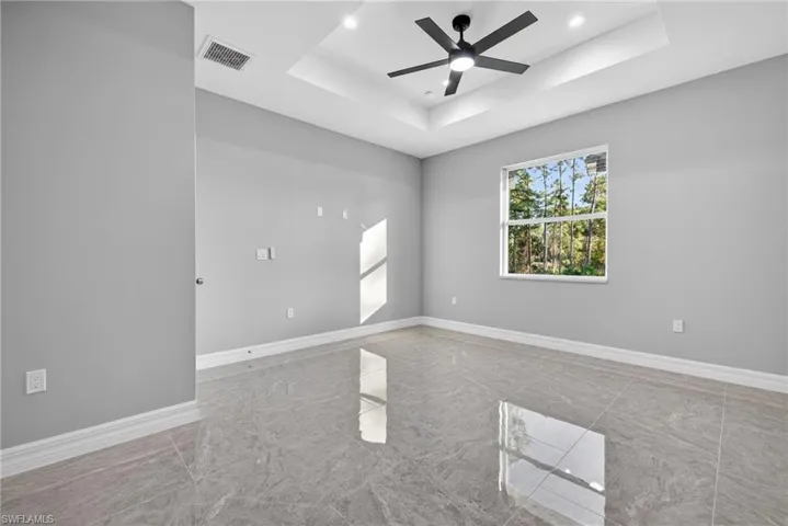 Empty room with a tray ceiling, a ceiling fan, and recessed lighting