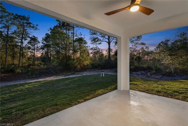 View of patio / terrace featuring ceiling fan and view of scattered trees