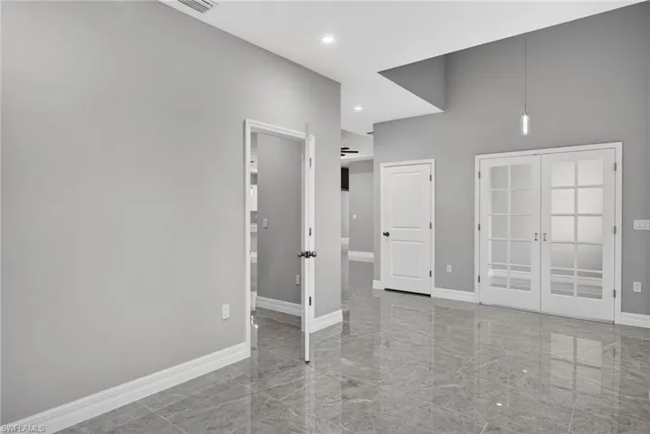 Empty room featuring french doors, recessed lighting, and a towering ceiling