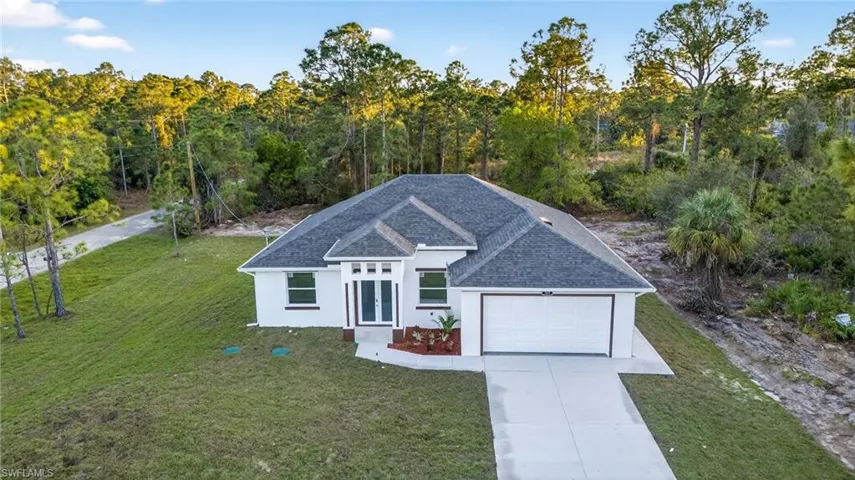 Ranch-style house featuring roof with shingles, a front yard, stucco siding, driveway, and an attached garage