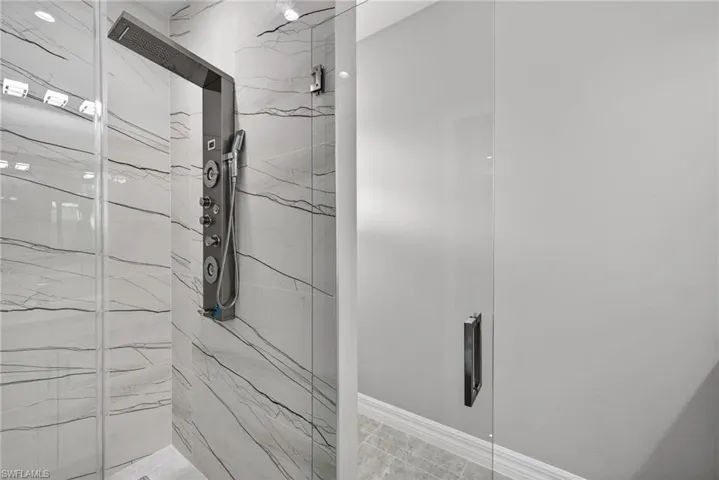 Bathroom with a marble finish shower and baseboards