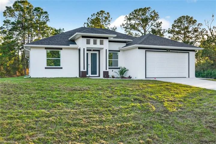 Prairie-style house with a front lawn, stucco siding, a garage, and driveway