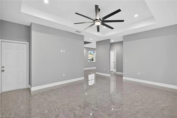 Unfurnished living room with recessed lighting, ceiling fan, a tray ceiling, and light marble finish flooring