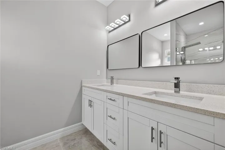 Full bath featuring double vanity and a stall shower