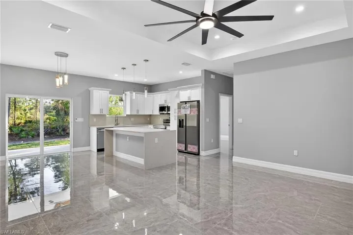 Kitchen with a center island, stainless steel appliances, a tray ceiling, pendant lighting, and recessed lighting