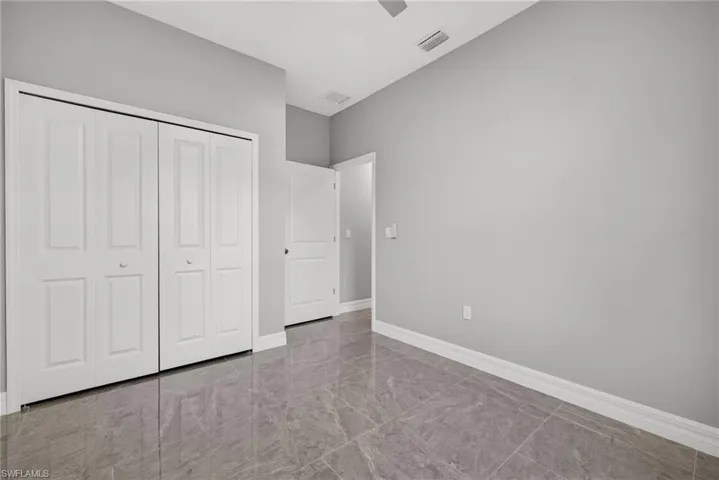 Unfurnished bedroom featuring a ceiling fan, a closet, and marble finish floors