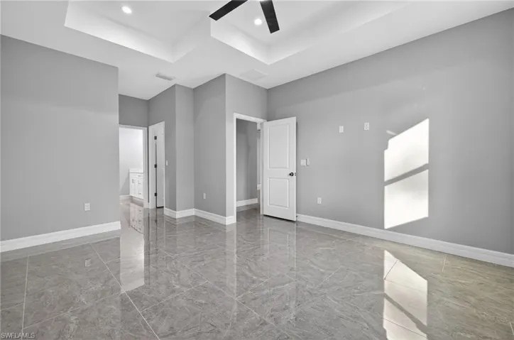 Unfurnished bedroom with ensuite bath, ceiling fan, recessed lighting, and light marble finish floors