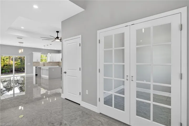 Hall with recessed lighting, light marble finish floors, and french doors