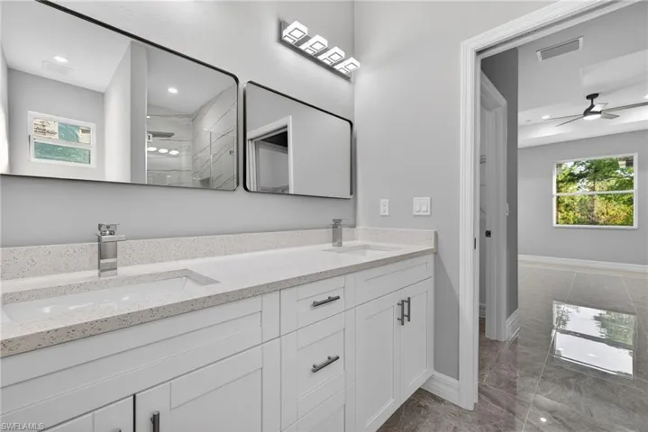 Full bath featuring a ceiling fan, a marble finish shower, double vanity, and recessed lighting