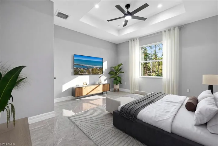 Bedroom with marble finish floors, ceiling fan, recessed lighting, and a tray ceiling