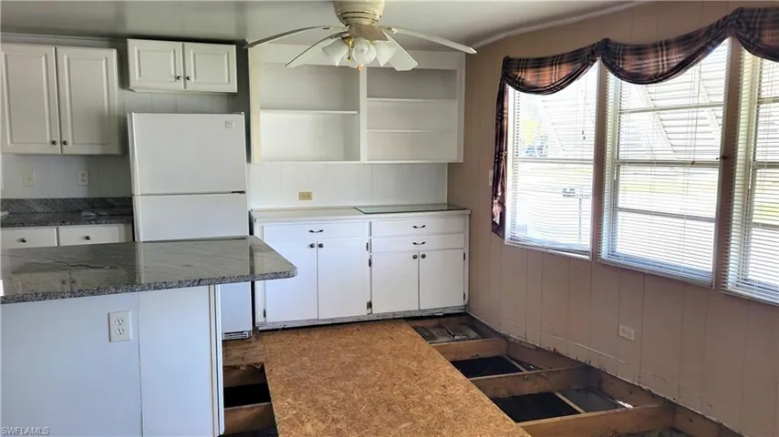 Kitchen featuring freestanding refrigerator, white cabinetry, a ceiling fan, and open shelves