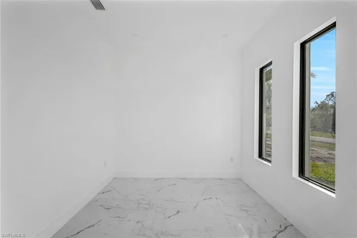 Unfurnished room with marble finish floors and plenty of natural light