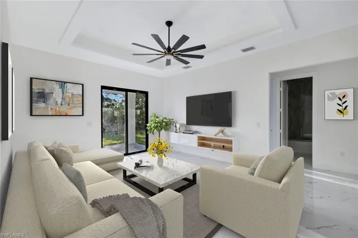 Living room featuring a raised ceiling, marble tiled flooring, and a ceiling fan