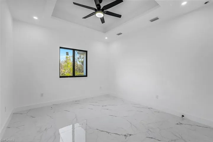 Spare room with recessed lighting, a raised ceiling, ceiling fan, and marble finish floors