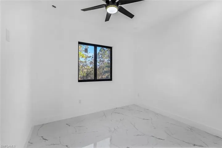 Empty room featuring light marble finish flooring and a ceiling fan