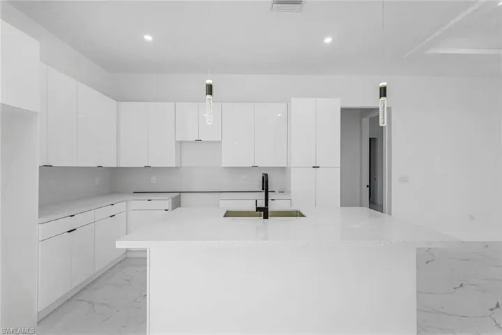 Kitchen featuring light marble finish floors, modern cabinets, white cabinets, and recessed lighting