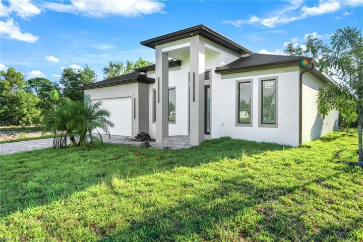 View of front facade featuring a garage, a front lawn, and stucco siding
