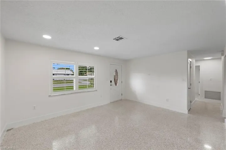 Empty room featuring a textured ceiling, recessed lighting, and dark aggregate flooring