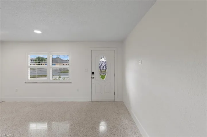 Entryway featuring a textured ceiling, speckle patterned floor, and recessed lighting