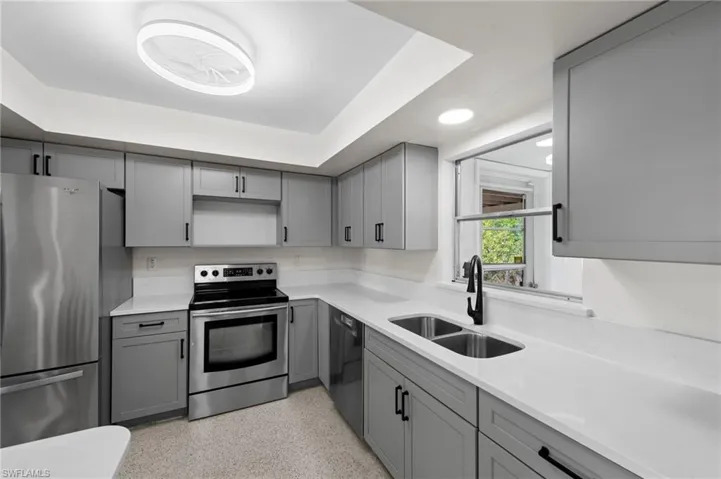 Kitchen with gray cabinets, stainless steel appliances, and light stone countertops
