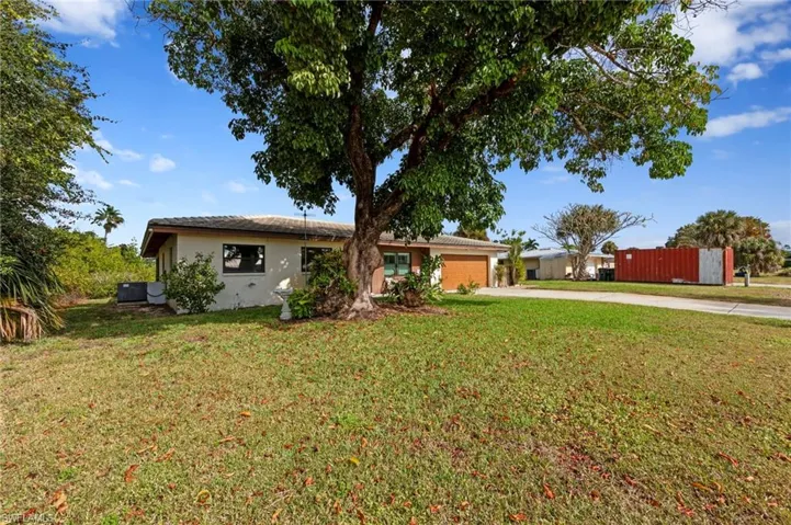 Ranch-style home featuring concrete driveway, an attached garage, a front lawn, and stucco siding