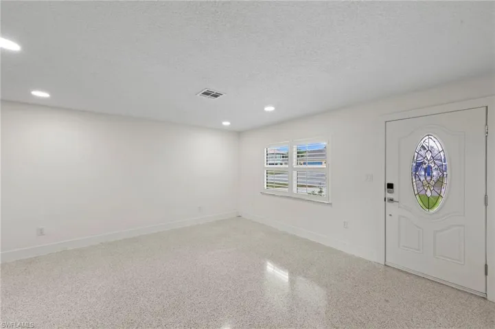 Entrance foyer with recessed lighting, a textured ceiling, and dark aggregate flooring