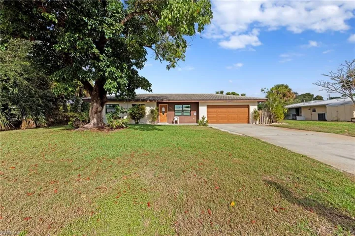 Ranch-style house with driveway, a garage, a front lawn, and stucco siding