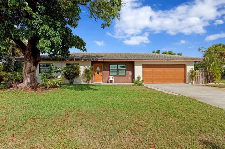 Single story home featuring driveway, stucco siding, a front lawn, and a garage