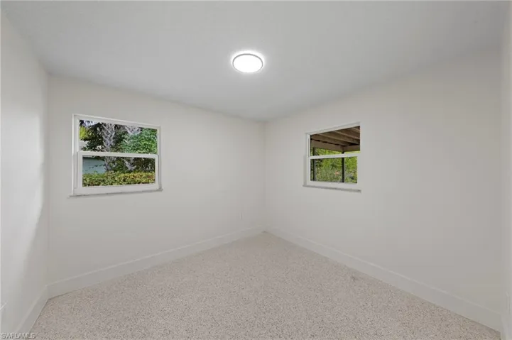 Empty room featuring baseboards and speckle patterned floor