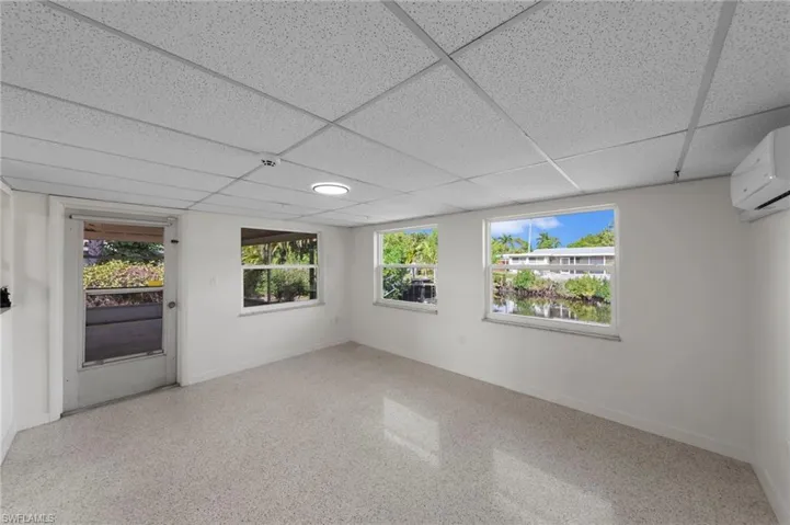 Spare room with a paneled ceiling, a wall mounted AC, and dark speckled floor