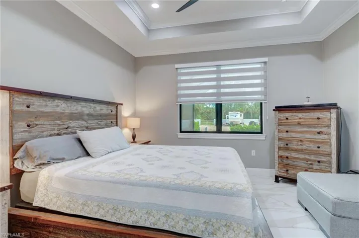 Bedroom featuring tile flooring, ceiling fan, a raised ceiling, and ornamental molding