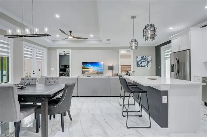 Tiled dining area with ceiling fan, a raised ceiling, and ornamental molding