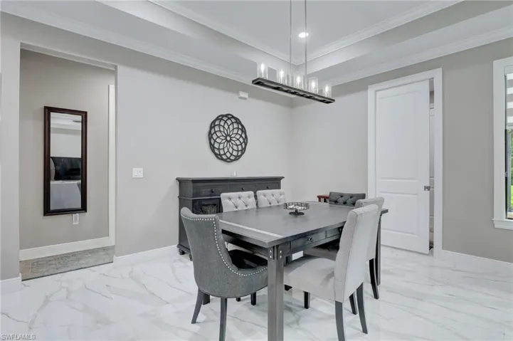 Dining space with a notable chandelier, ornamental molding, and light tile floors