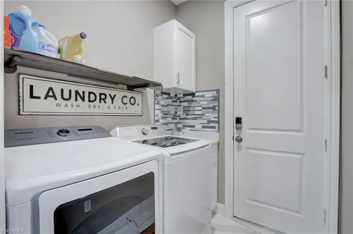 Washroom with independent washer and dryer, cabinets, and light tile floors