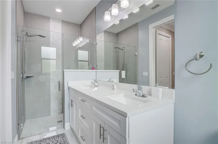 Bathroom with double vanity, walk in shower, and tile floors