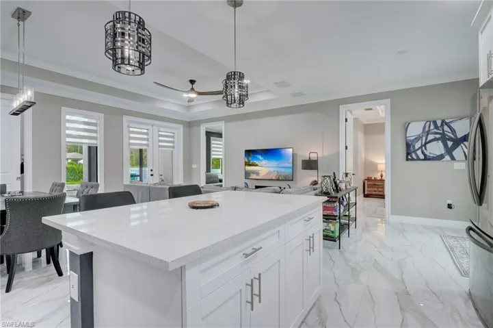 Kitchen with decorative light fixtures, white cabinetry, ornamental molding, and a kitchen island