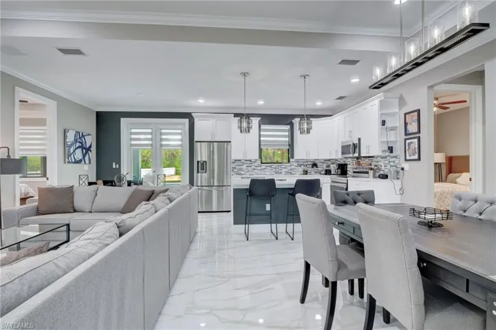 Dining area featuring ceiling fan with notable chandelier, crown molding, and light tile flooring