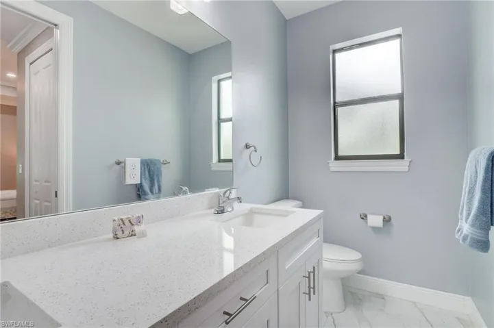 Bathroom with toilet, tile floors, and large vanity